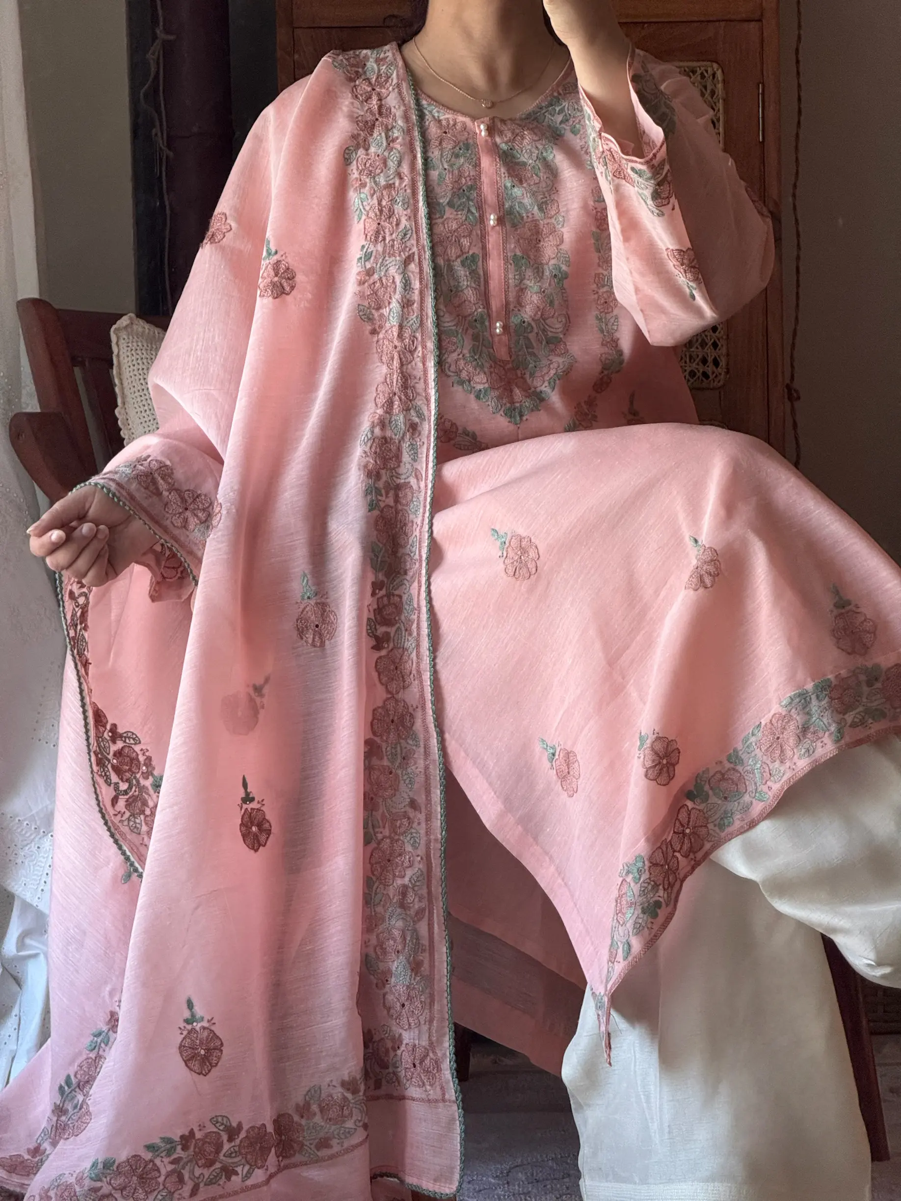 a woman sitting and wearing a light pink traditional dress from oni handmade.